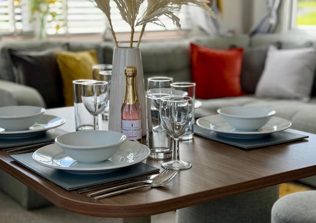 a table with plates and glasses and a bottle of wine at Rosie's Seton Retreat in Port Seton