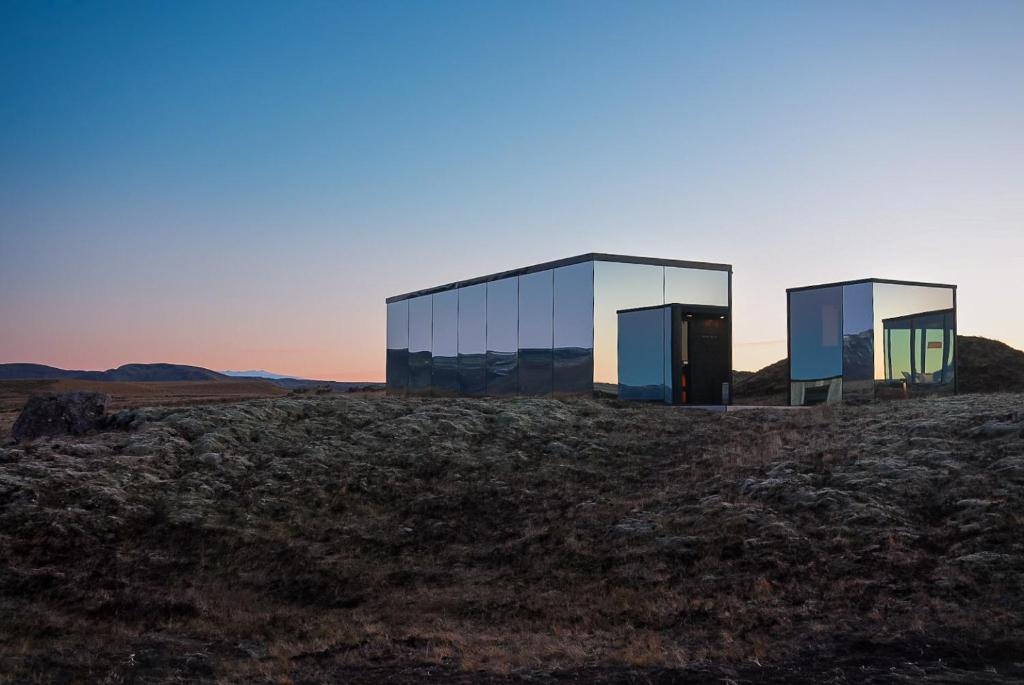 two glass buildings sitting on top of a field at ÖÖD Hekla Horizon - Mirror Houses in Hella