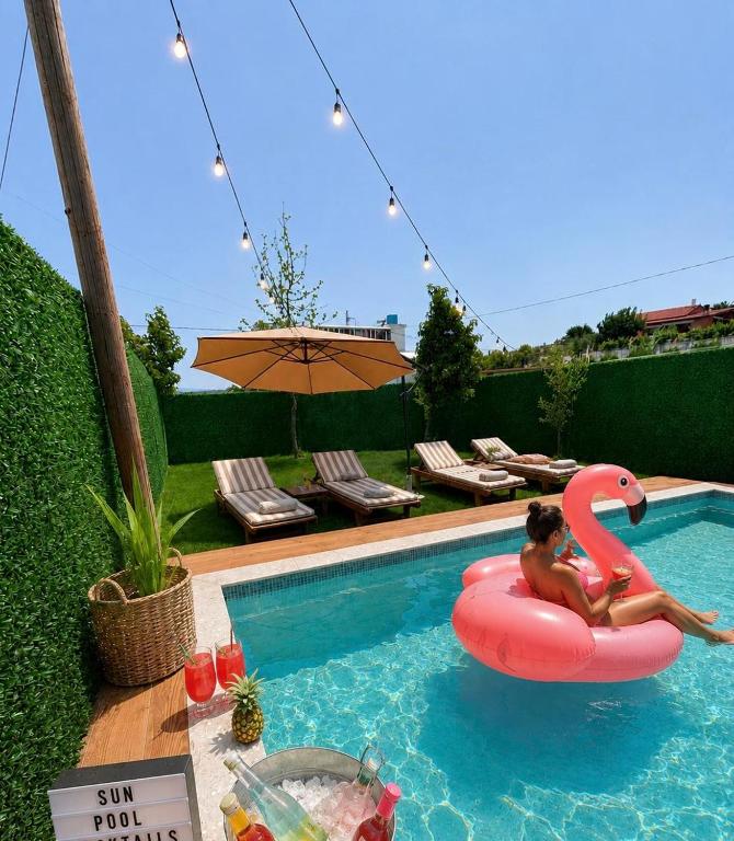 a woman riding a pink flamingo in a swimming pool at Wooden Villa Eilin 3 in Tirana