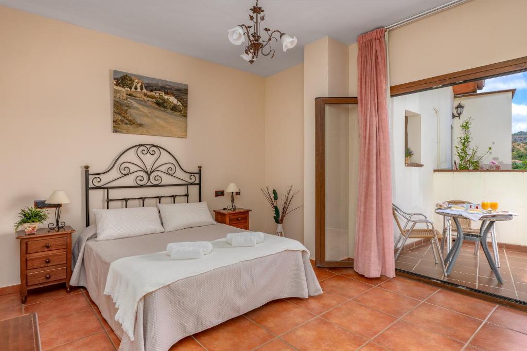 a bedroom with a large bed and a table at Hotel Balcón de los Montes in Colmenar