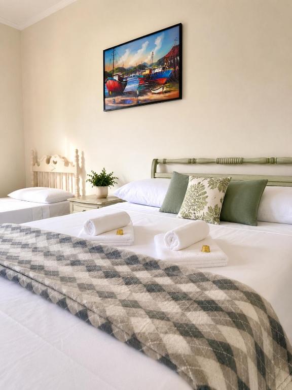 a bedroom with a white bed with two towels on it at Pousada Casa Contos de Minas in Ubatuba