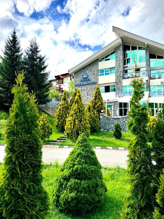 a group of trees in front of a building at Hotel Alexandros Busteni by Genco & Restaurant Miorita in Buşteni