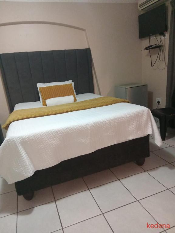 a bedroom with a large bed with a white blanket at Moonlight Guesthouse in Bloemfontein