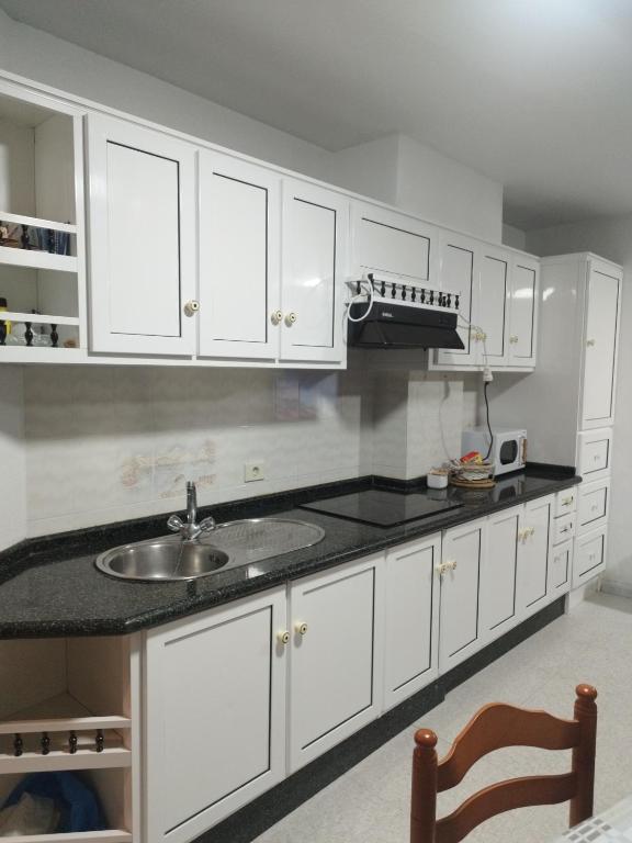 a kitchen with white cabinets and a sink at Vivienda Turística Ático in Laxe