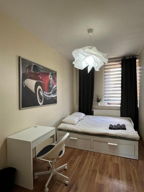 a bedroom with a bed with a desk and a car picture at Fajrant Rooms Katowice in Katowice