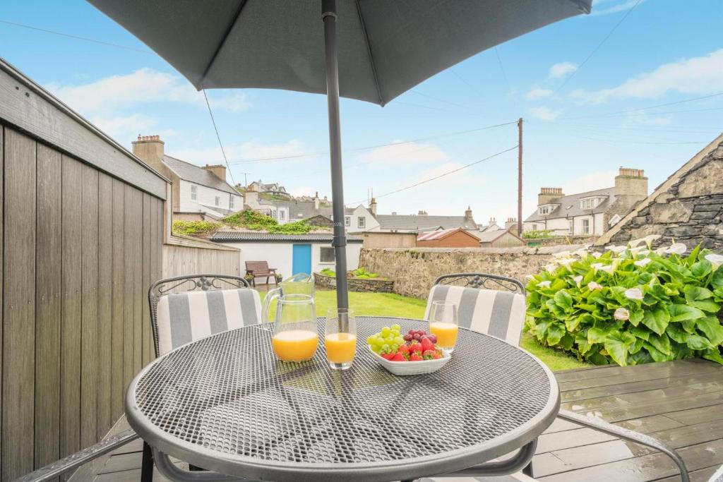 a table with two glasses of orange juice and a bowl of fruit at 2 Bed in Portpatrick oc-p43756 in Portpatrick