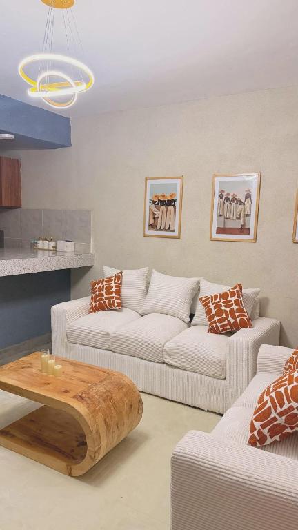 a living room with two white couches and a coffee table at Kaizen Homes in Homa Bay