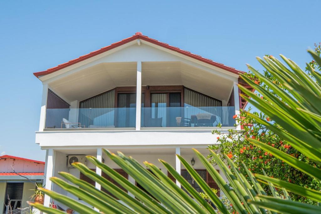 a house with a balcony with chairs and trees at Zeusplace Olympus Casa in Paralía Skotínis