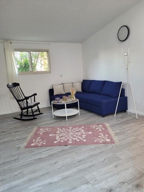 a living room with a blue couch and a table at Serenity Cabin in Dalia in Dāliyat el Karmil