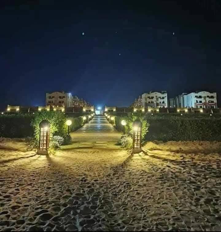 a long walkway at night with buildings and lights at لاسيرينا عيون موسى LaSerinaللعائلات in Ras Sedr