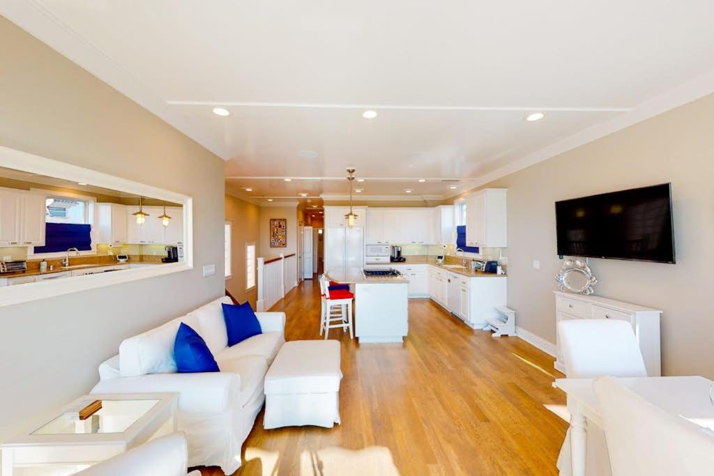 a living room with white furniture and a kitchen at Gull Cottage in Seal Beach