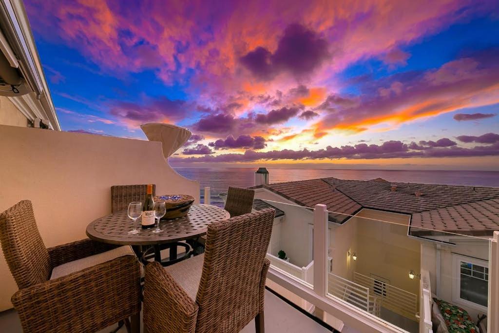 a balcony with a table and chairs with a sunset at San Clemente Ocean Luxury Bluff Top in San Clemente