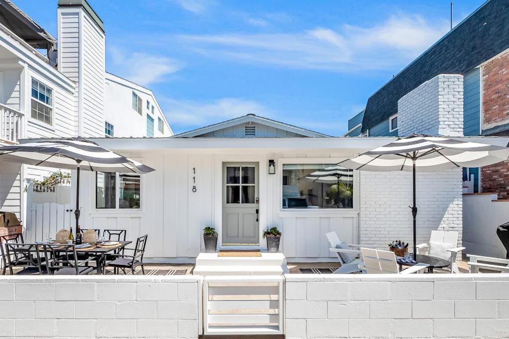 a white house with a patio with tables and umbrellas at Newport Coastal Compound in Newport Beach