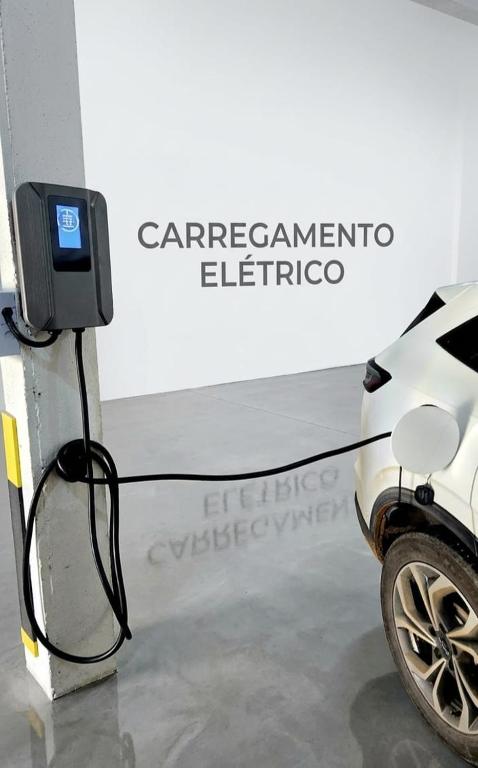 a white car is plugged into a charger at JK QUITINETES ECONOMICO com garagem CENTRAL in Pelotas
