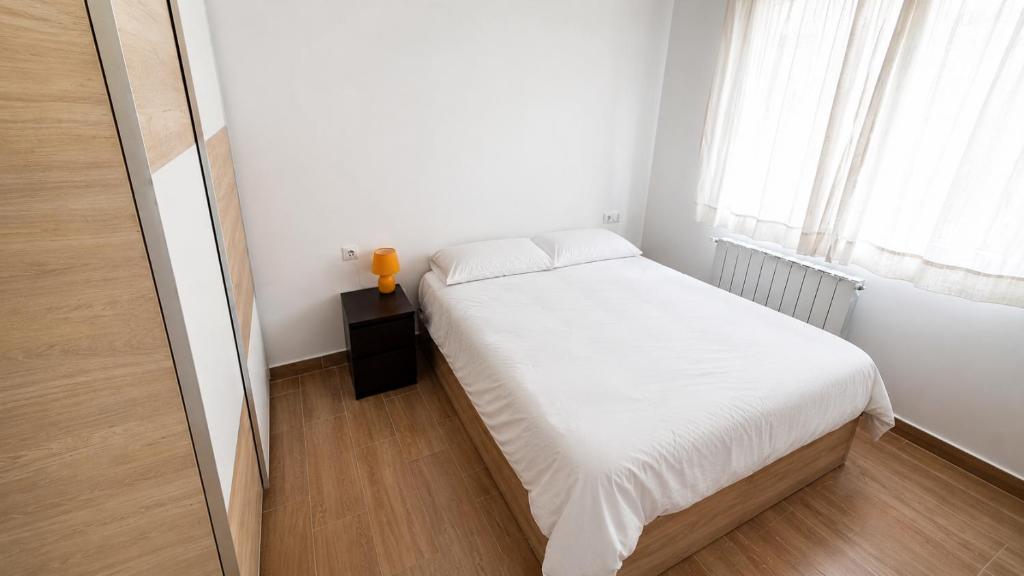 a small bedroom with a white bed and a window at Descansa Las Mareas in Santander