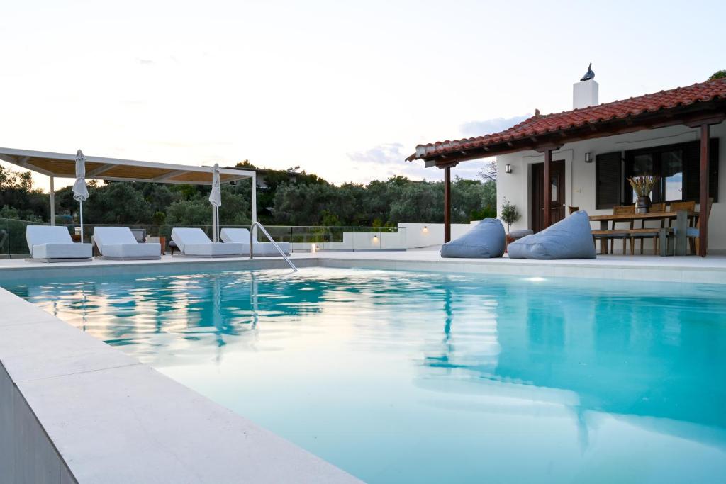 a swimming pool with chairs and a house at Villa Emerald Diamond in Kolios