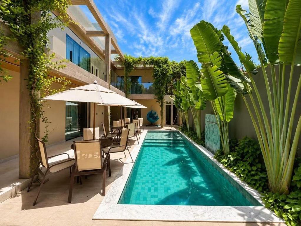 a swimming pool with chairs and an umbrella next to a building at LAWAKE House pipa Studios e apartamentos nomads in Pipa