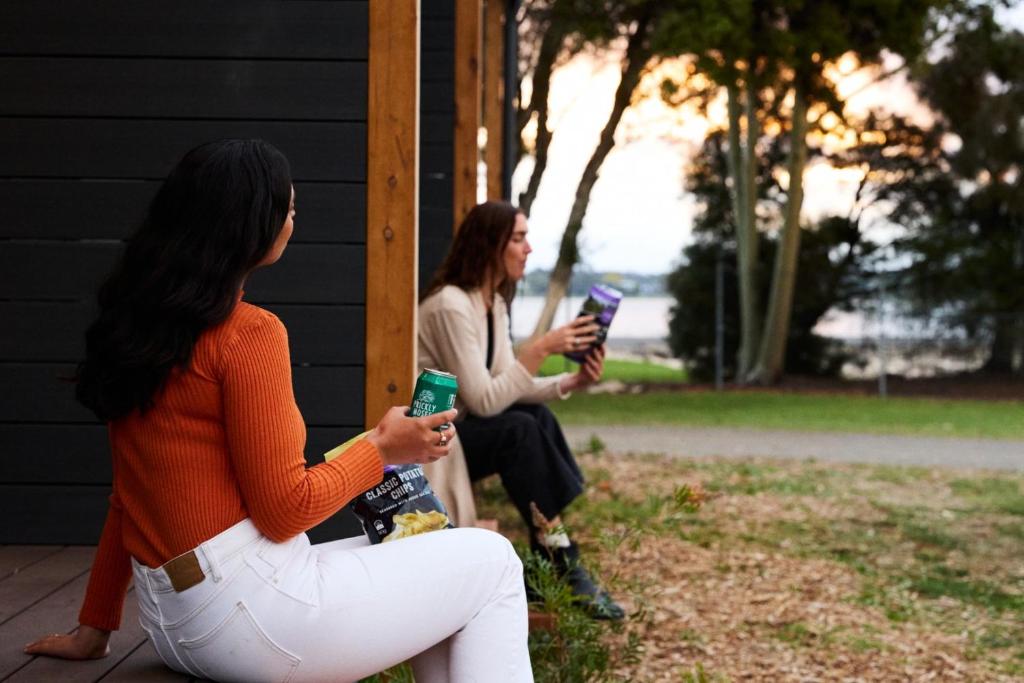 two women sitting on a porch holding their cell phones at Lake Colac Holiday Park in Colac