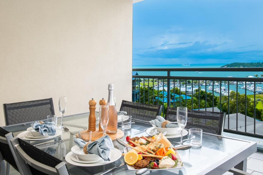 a dining table with food and a view of the ocean at Club Airlie in Airlie Beach