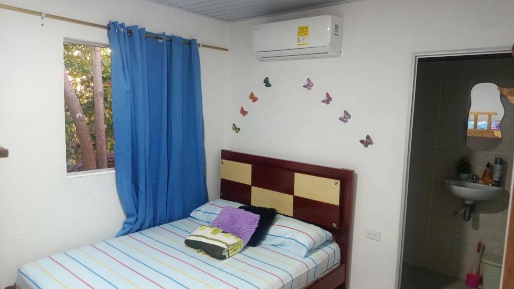 a bedroom with a bed with blue curtains and a sink at Los Clemones in Rincón
