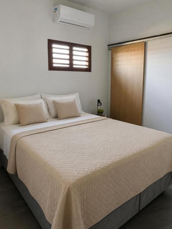 a bedroom with a large white bed with a window at Tigre Beach House in Trairi