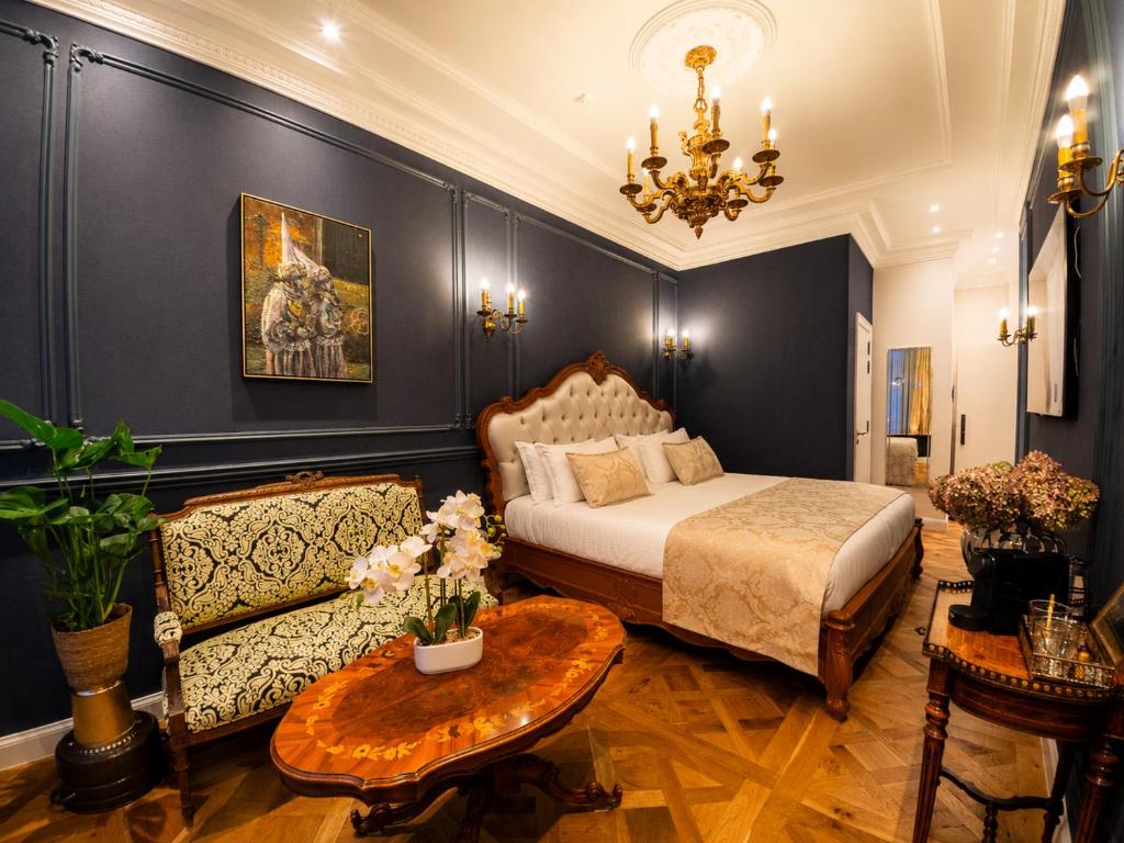 a bedroom with a bed and a couch and a table at Strands Of Time Hotel Bruges in Bruges