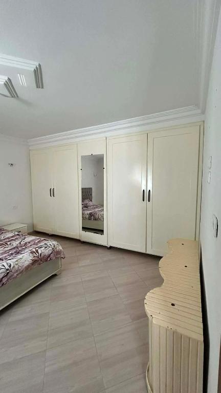 a bedroom with a bed and white cabinets and a table at Marsa plage kelibia in Kelibia