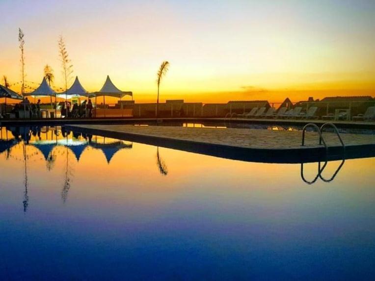 a pool of water with a sunset in the background at Catarina Condomínio Clube in Mairinque