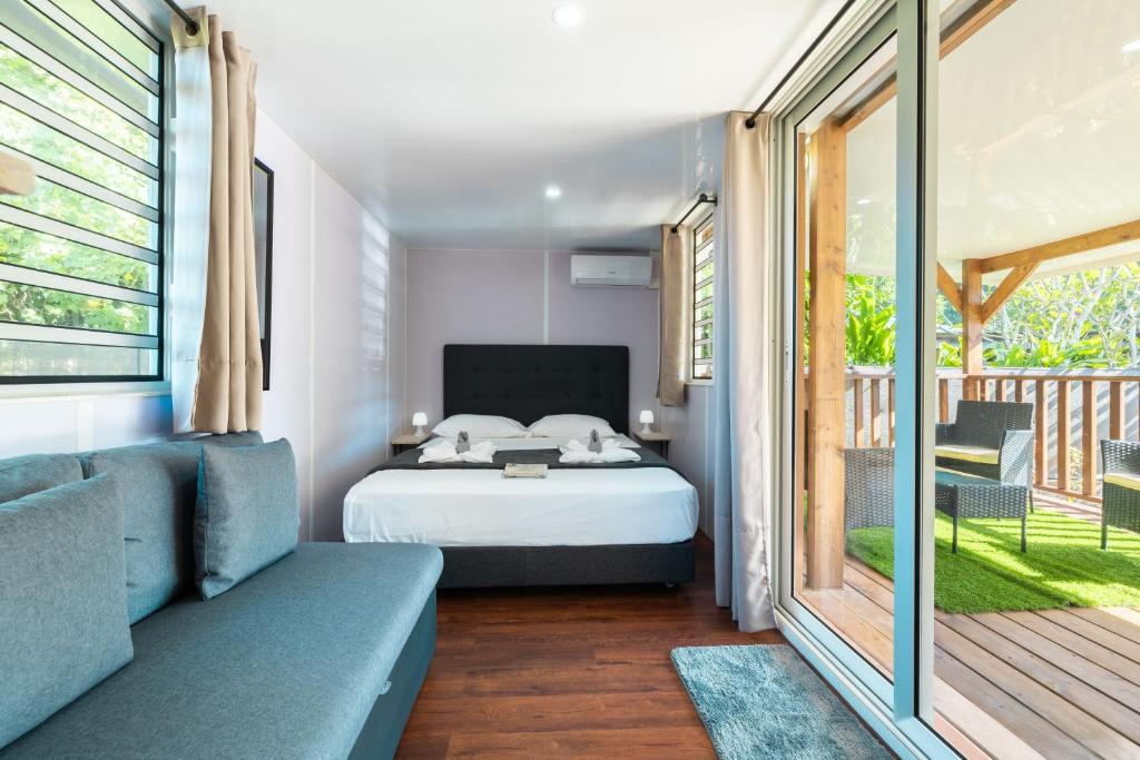 a bedroom with a bed and a balcony at Fare AGT Moorea in Afareaitu