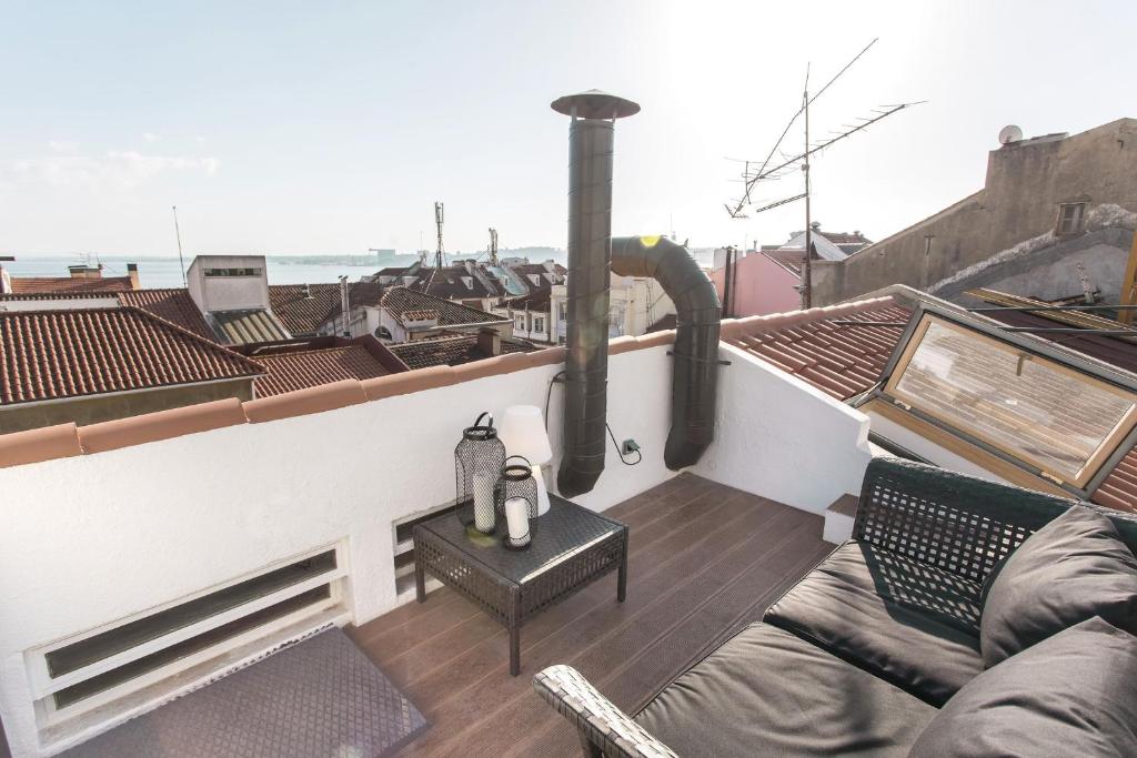 a balcony with a couch and a table on a roof at LovelyStay - Cais Apartment River View in Lisbon