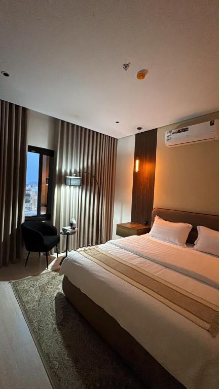 a hotel room with a large bed and a chair at شقة أنيقة جديده في قلب أبها in Abha