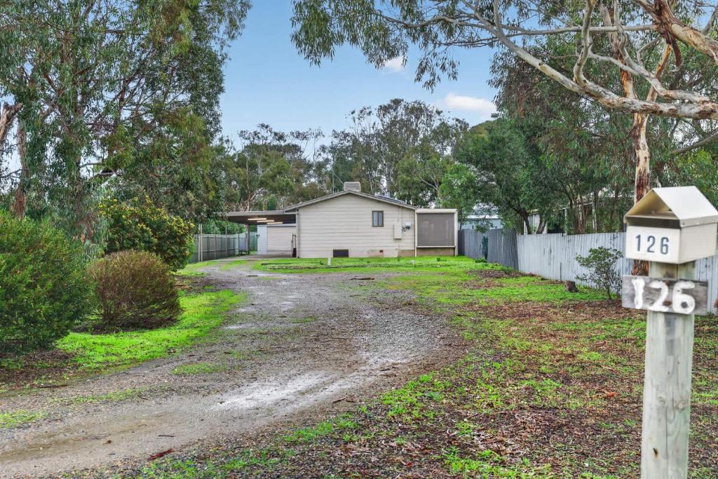 a house with a road in front of a fence at The Brynes Hideaway - On Brynes Road in Goolwa