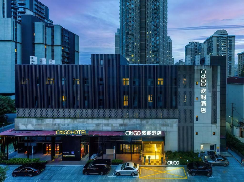 a building with cars parked in a parking lot at CitiGO Hotel Shanghai Xujiahui in Shanghai