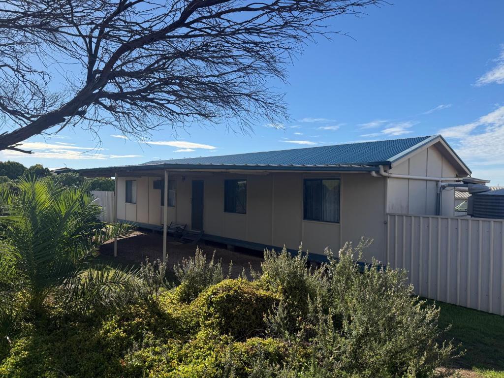 a white house with a fence and bushes at Flahertys Retreat in Point Turton