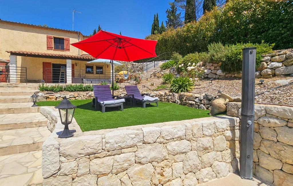 a red umbrella in a yard with chairs and a house at Nice Home In Peymeinade in Peymeinade