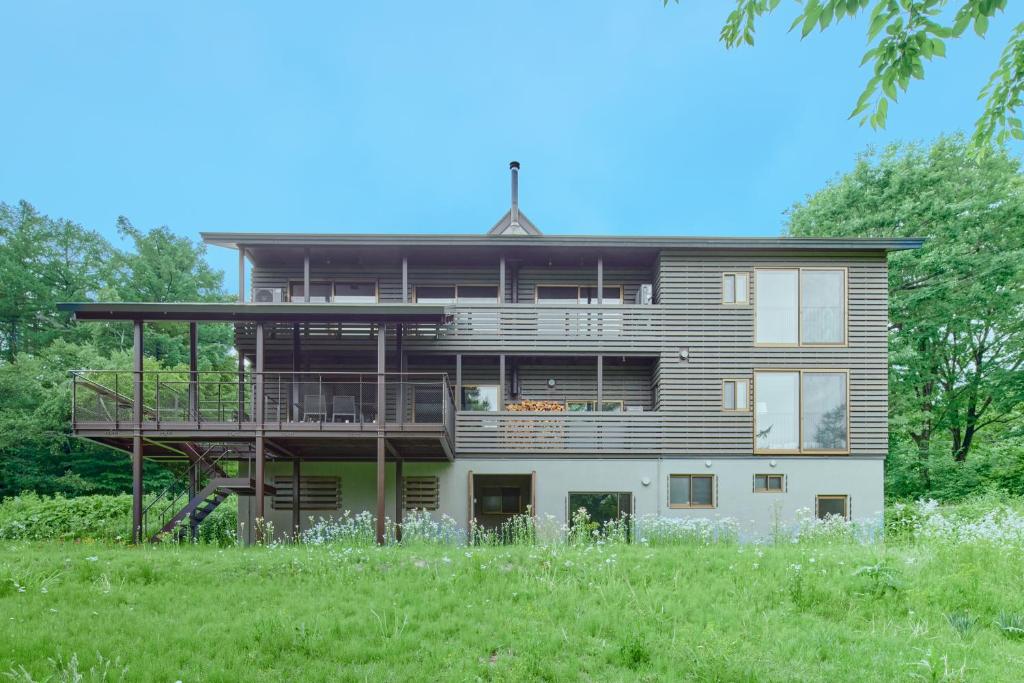 a large house with a deck on a field at Villa El Cielo Myoko in Myoko