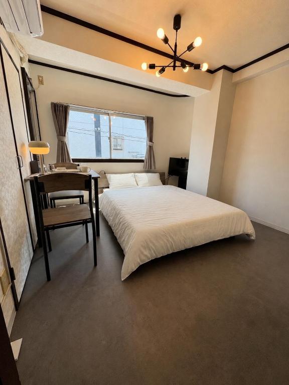 a bedroom with a bed and a table and a chair at Palette Kuhonji in Kumamoto