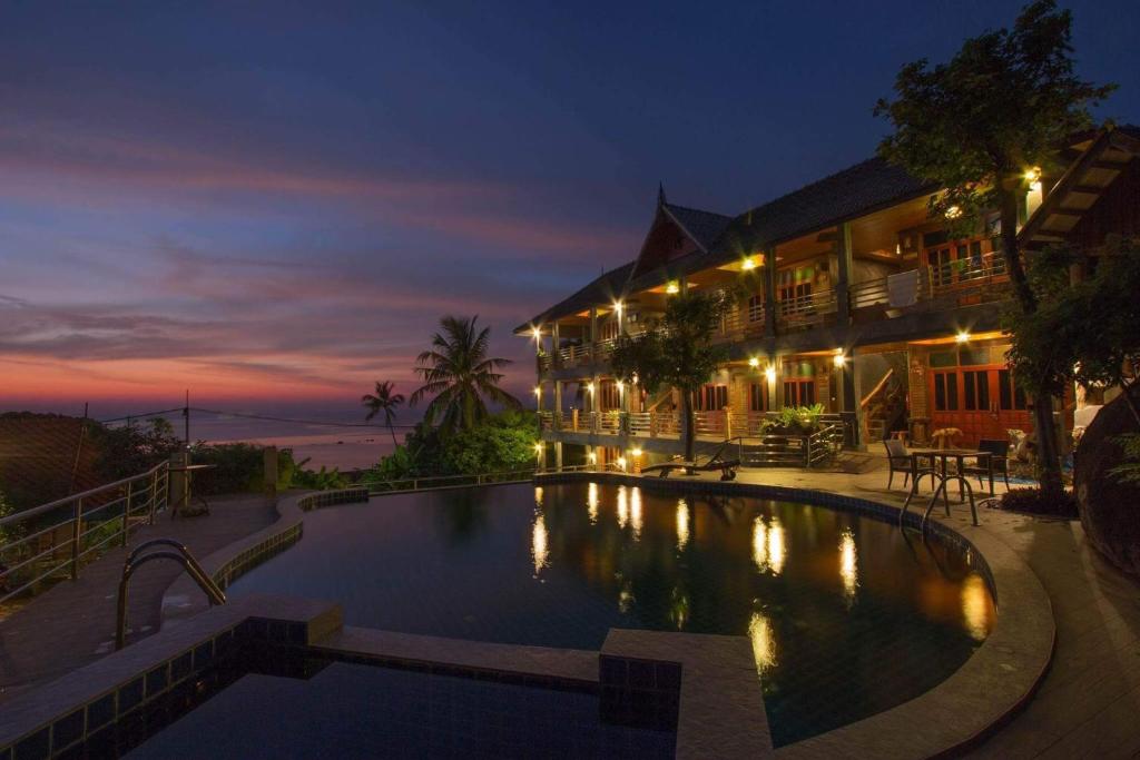 - une piscine en face d'une maison la nuit dans l'établissement Sea Rock Resort, à Haad Pleayleam