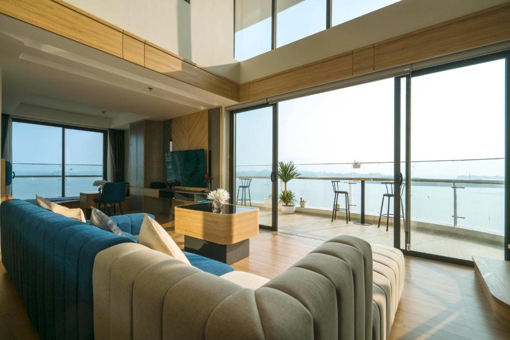 a living room with a blue couch and large windows at Homestay Alacarte - Icon40 - New Life - Villa Lotus in Ha Long