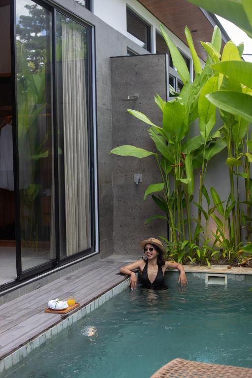 a woman in a hat is in a swimming pool at Anasera Villas Echo Beach Canggu in Canggu