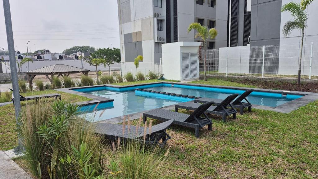 a swimming pool with chairs and a table in front of a building at Your Perfect Rest Apartment with Pool and AC in Playa de Vacas