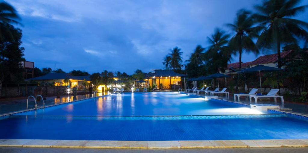 a large swimming pool with chairs and palm trees at night at Herbal Resort & Spa 3 minutes to the beach in Phú Quốc