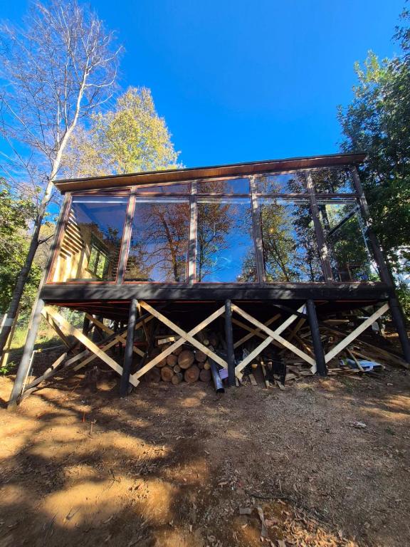 a cabin with a glass roof and a pile of logs at Cabañas Alturas Don Gaspar in Recinto