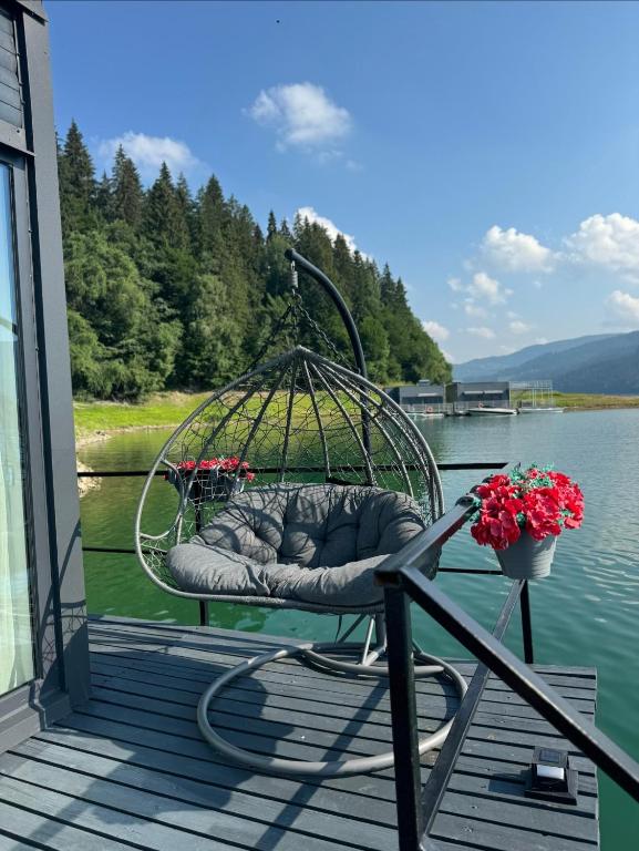 a swing sitting on a porch next to the water at Black Swan Lakehouse in Bicaz