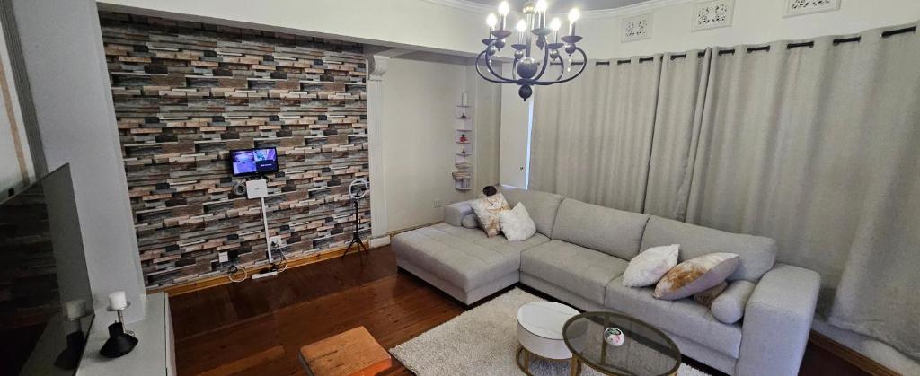 a living room with a couch and a brick wall at Lilly by the road in Durban