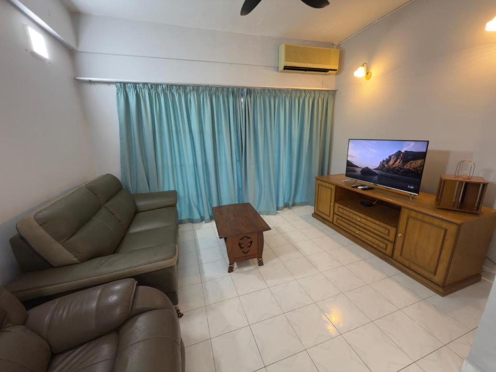 a living room with a couch and a television at Tiktoki Apartment 15C Kijal in Kijal
