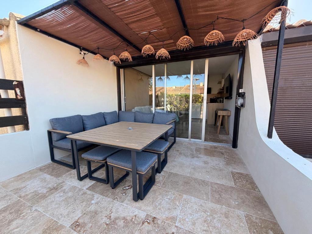 a patio with a wooden table and chairs at Sexty-nine, villa 69 héliovillage in Cap d'Agde