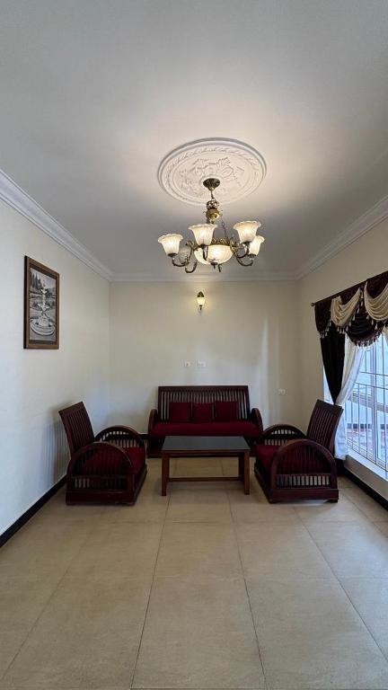 a living room with couches and a table and a ceiling at Green woods stays in Ooty