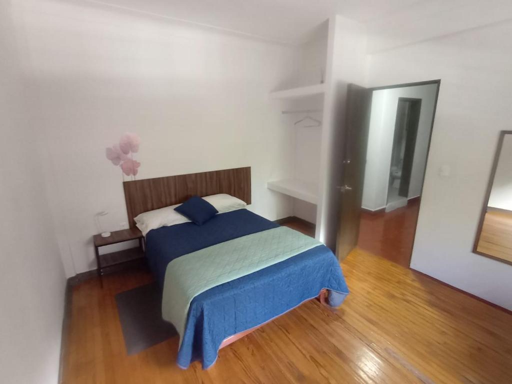 a bedroom with a bed with a blue blanket on it at Hostal Schultz in Mexico City