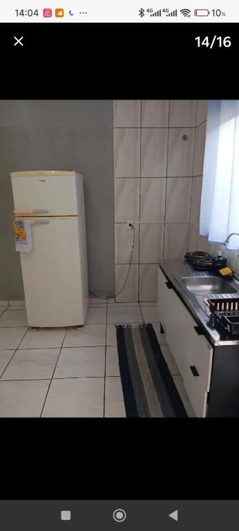 a kitchen with a white refrigerator and a stove at KITNET - Completa e Individual - Pousada Itapetininga in Itapetininga